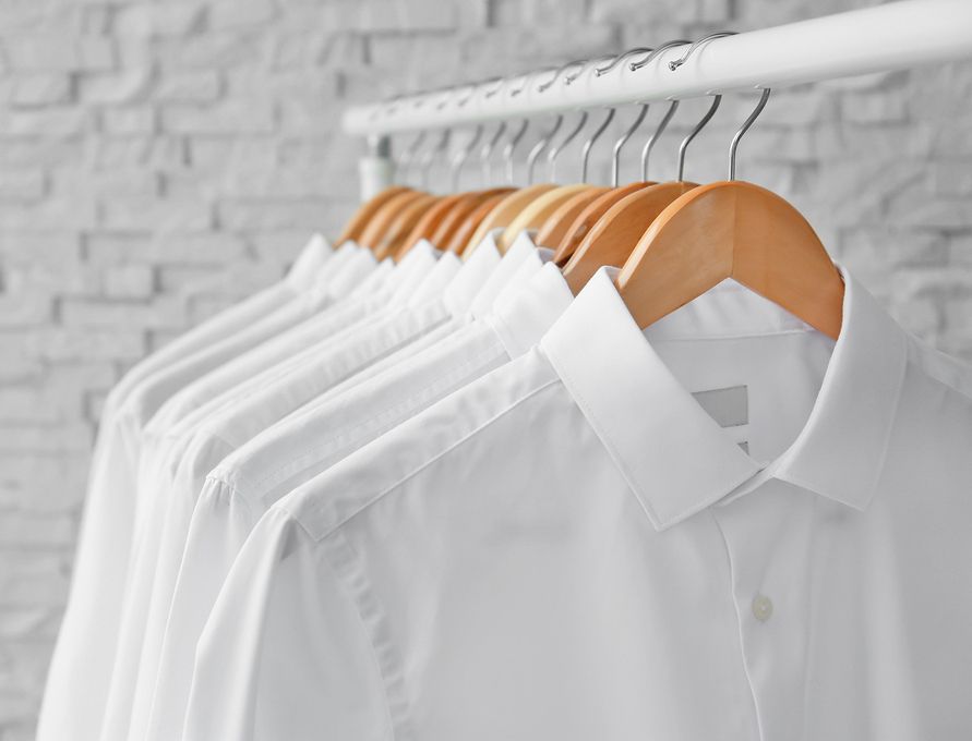 Mehrere weiße Hemden hängen an einer Kleiderstange